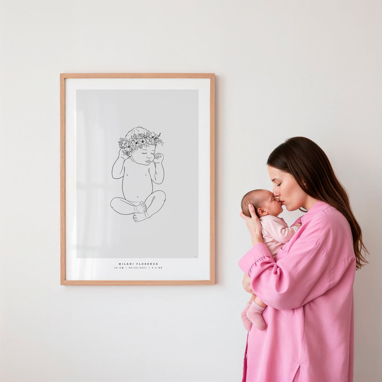 Mother kissing her baby next to a personalized birth poster with a flower crown.