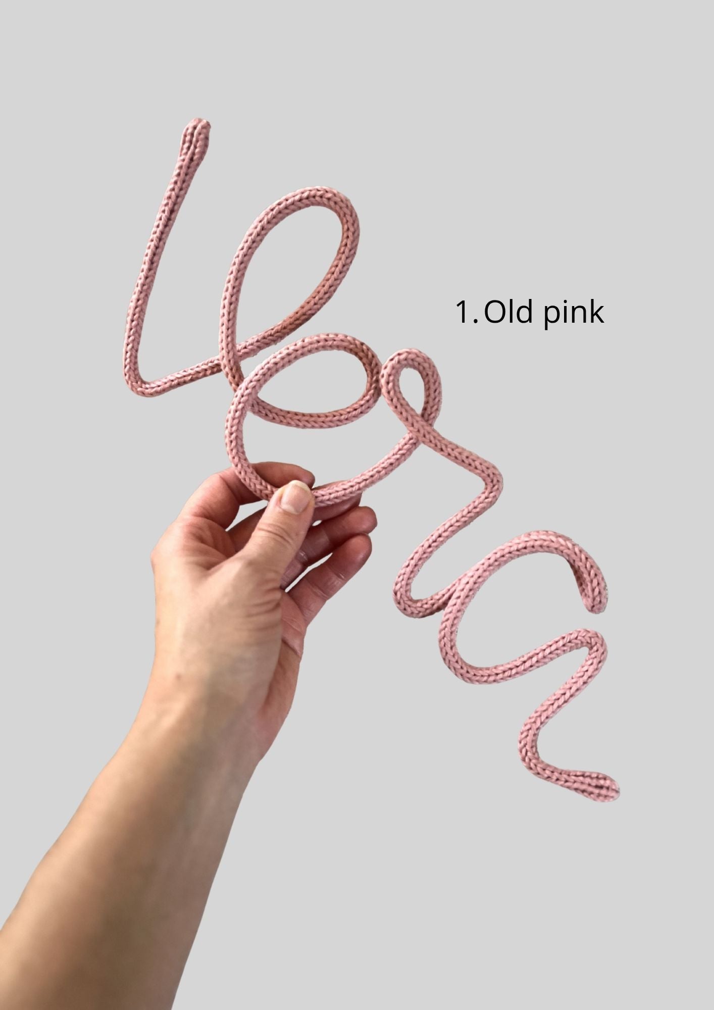 Hand som håller ett stickad namn i färgen rosa