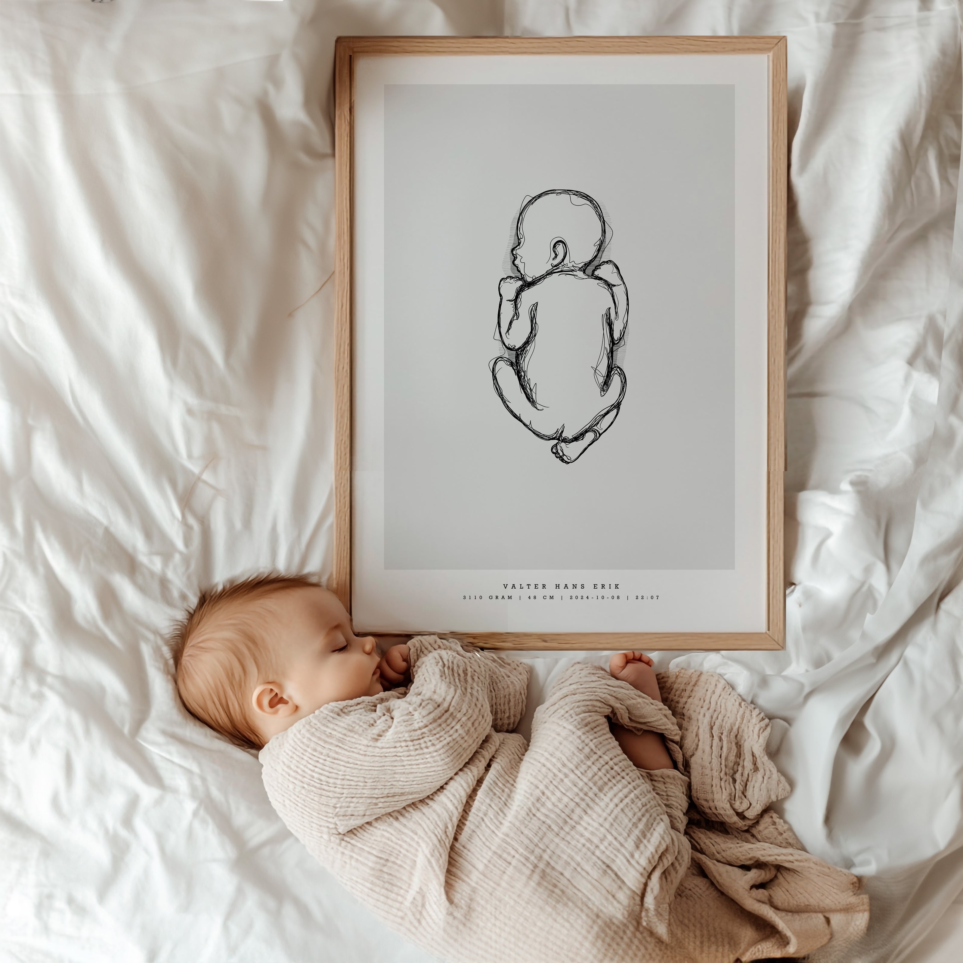Baby lying next to their personalized birth poster in the nursery.